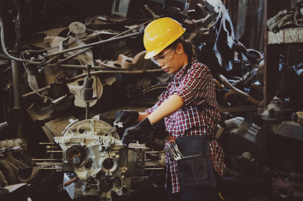 pexels-photo-1108101-1108101 Woman engineer wearing safety gear, working on machine repair in an industrial setting.